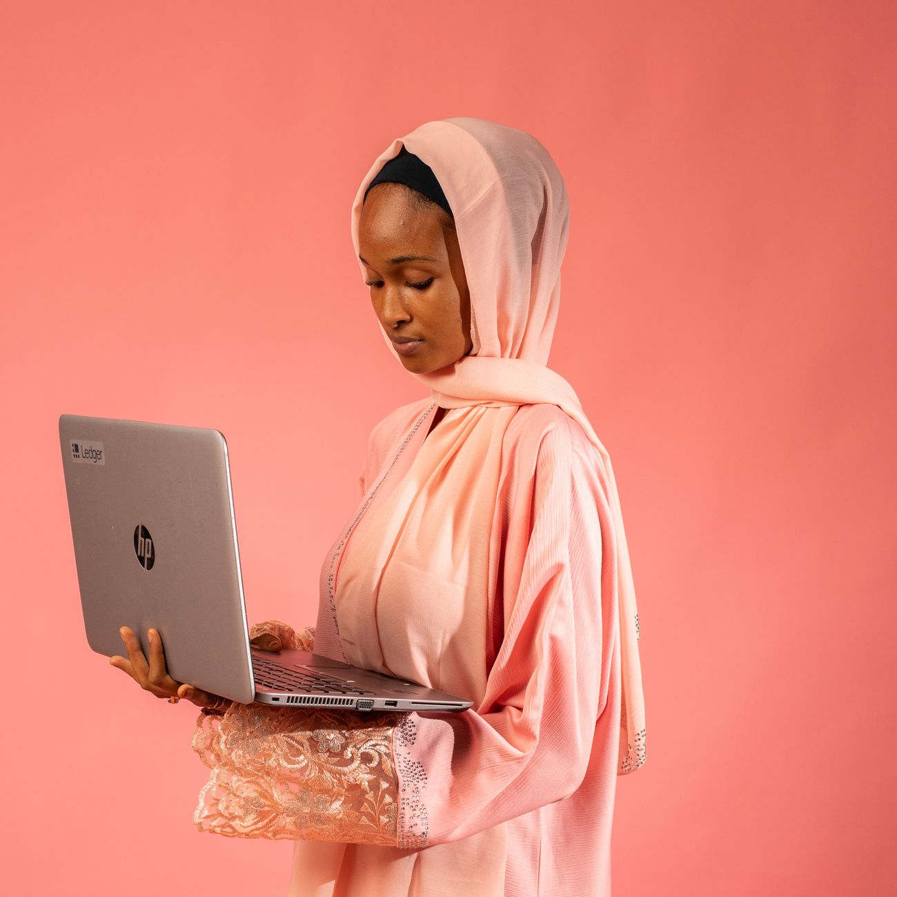 Person using a laptop against a pink background